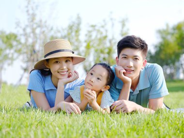 Üç kişilik mutlu bir aile çimlerin üzerinde