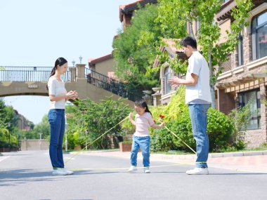 Dışarıda ip atlayan mutlu bir aile.