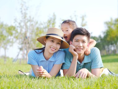 Üç kişilik mutlu bir aile çimlerin üzerinde