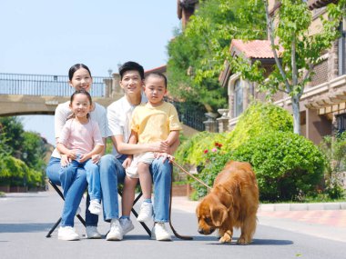 Dört kişilik mutlu bir aile ve açık hava fotoğrafında evcil bir köpek.