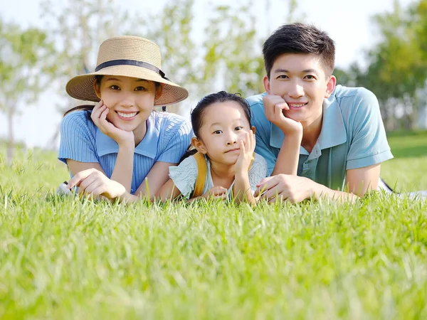 Família feliz de três na grama — Fotografia de Stock