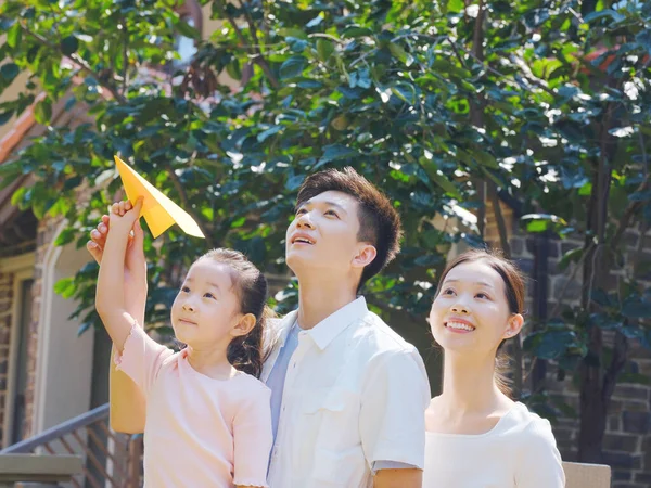 Üç kişilik mutlu bir aile dışarı kağıt uçaklar fırlatıyor. — Stok fotoğraf
