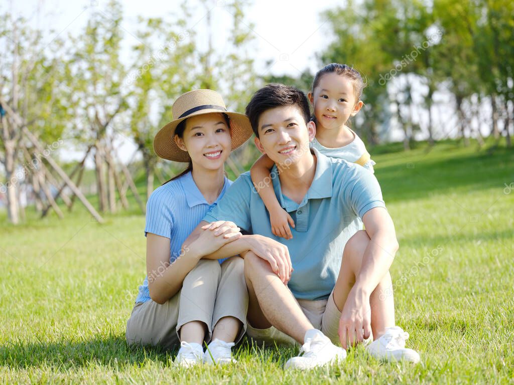 Happy family of three sitting on the grass
