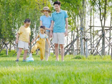 Parkta oynayan dört kişilik mutlu bir aile.