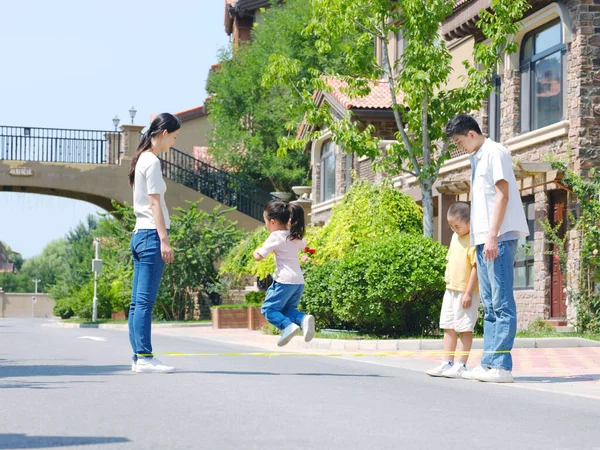 Família feliz de quatro pulando corda ao ar livre — Fotografia de Stock