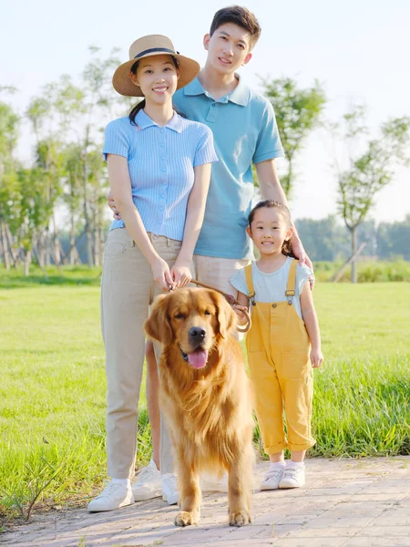 Família feliz de três e cão de estimação no parque — Fotografia de Stock