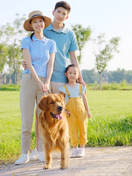 Família feliz de três e cão de estimação no parque — Fotografia de Stock