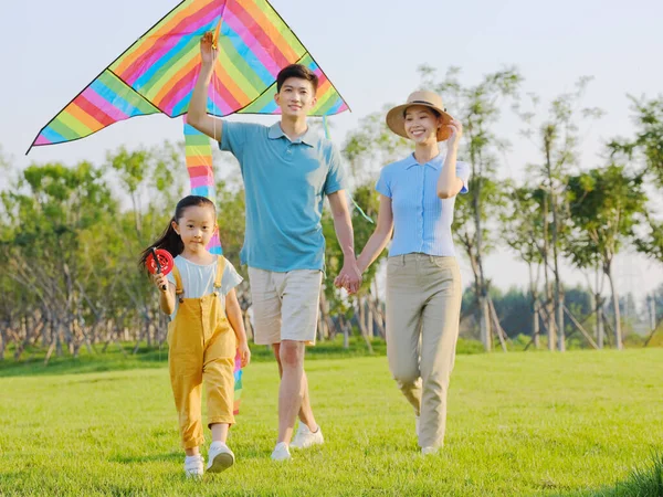 Parkta uçan üç kişilik mutlu bir aile. — Stok fotoğraf