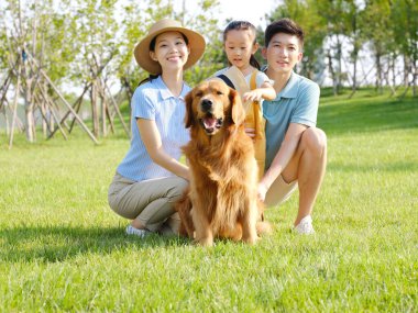 Üç kişilik mutlu bir aile ve açık hava fotoğrafında evcil bir köpek.