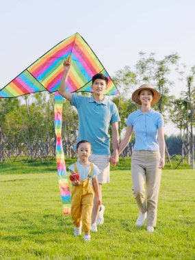 Parkta uçan üç kişilik mutlu bir aile.