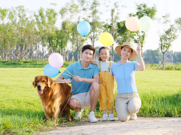Família feliz de três e cão de estimação no parque — Fotografia de Stock