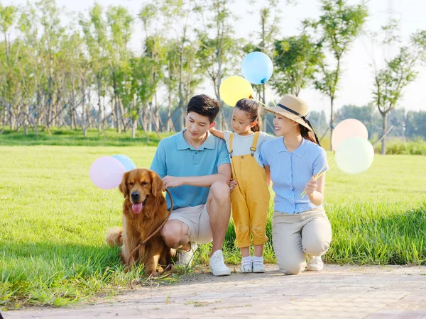 Família feliz de três e cão de estimação no parque — Fotografia de Stock