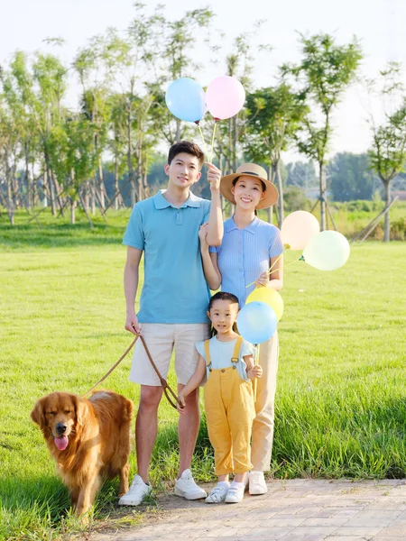 Happy family of three and pet dog in the park