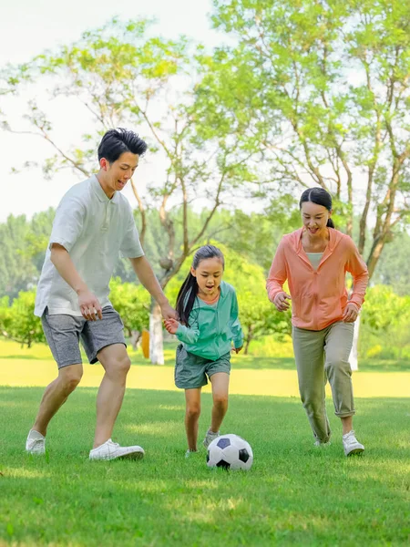 Heureuse famille de trois personnes jouant au football dans le parc — Photo