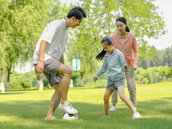 Heureuse famille de trois personnes jouant au football dans le parc — Photo