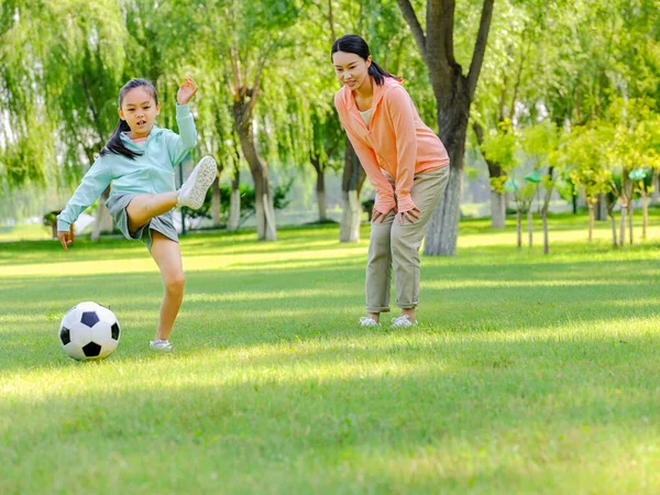 Gelukkige moeder en dochter spelen voetbal in het park — Stockfoto