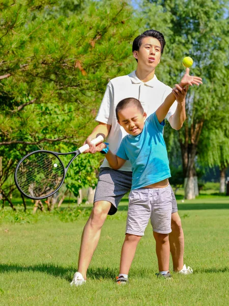 Feliz padre e hijo están jugando al tenis en el parque — Foto de Stock