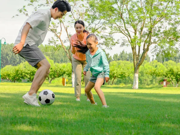 Familia feliz de tres jugando al fútbol en el parque — Foto de Stock