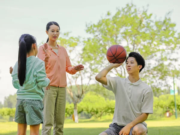 Família feliz de três jogando basquete no parque — Fotografia de Stock