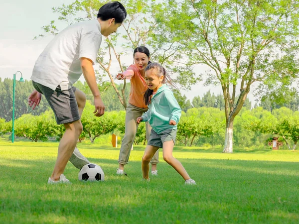 Familia feliz de tres jugando al fútbol en el parque — Foto de Stock