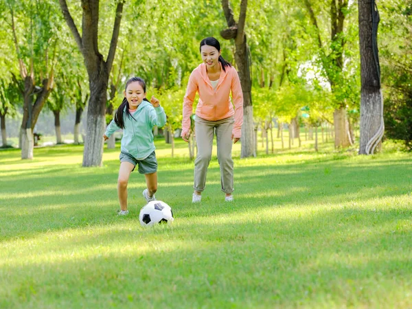 Ευτυχισμένη μητέρα και κόρη παίζουν ποδόσφαιρο στο πάρκο. — Φωτογραφία Αρχείου