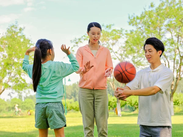 Família feliz de três jogando basquete no parque — Fotografia de Stock