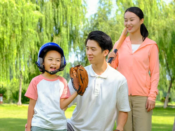 Boldog háromtagú család baseballozik a parkban. — Stock Fotó