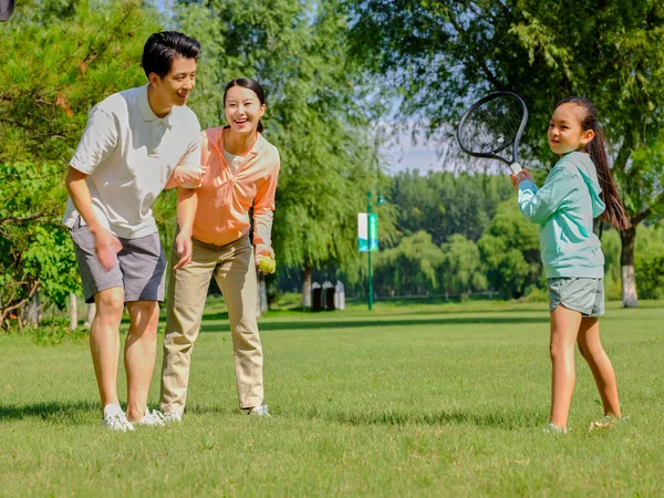 Família feliz de três jogando tênis no parque — Fotografia de Stock