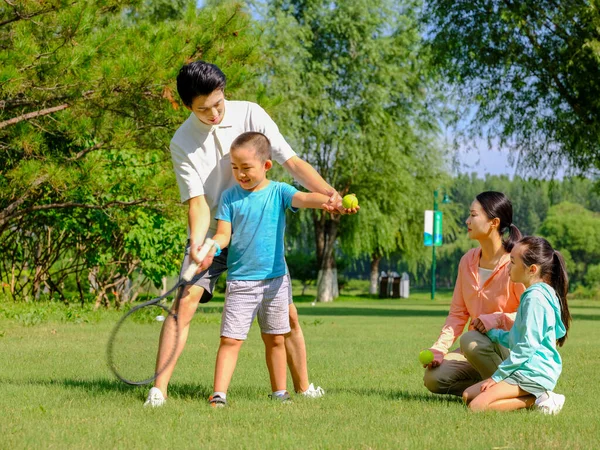 Família feliz de quatro jogando tênis no parque — Fotografia de Stock
