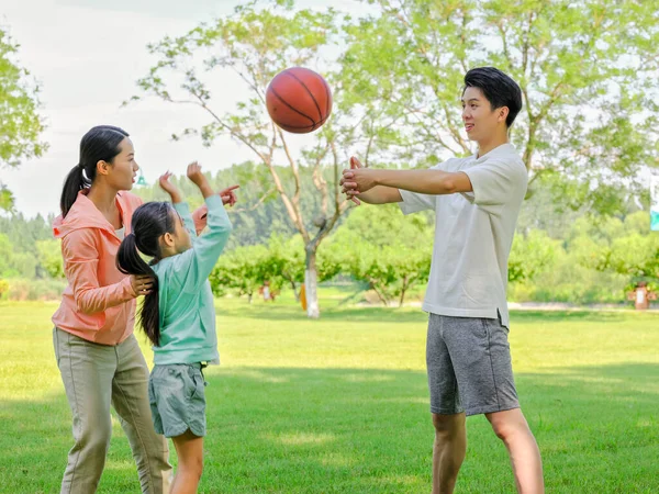 Família feliz de três jogando basquete no parque — Fotografia de Stock