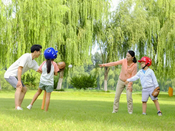 Šťastná čtyřčlenná rodina hraje baseball v parku — Stock fotografie