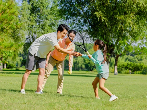 Ευτυχισμένη οικογένεια τριών παιδιών που παίζουν τένις στο πάρκο — Φωτογραφία Αρχείου