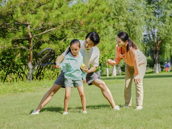 Boldog háromtagú család teniszezik a parkban. — Stock Fotó