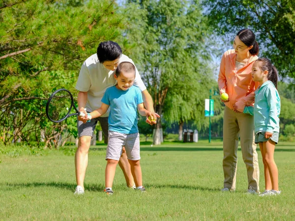 Счастливая семья из четырех человек играет в теннис в парке — стоковое фото