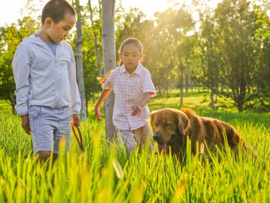 Parkta köpek gezdiren iki mutlu çocuk.