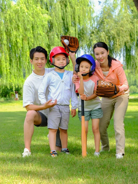 Boldog négytagú család baseballozik a parkban. — Stock Fotó