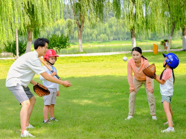 Família feliz de quatro jogando beisebol no parque — Fotografia de Stock