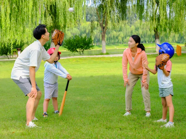 Família feliz de quatro jogando beisebol no parque — Fotografia de Stock