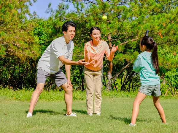 Heureuse famille de trois personnes jouant au tennis dans le parc — Photo