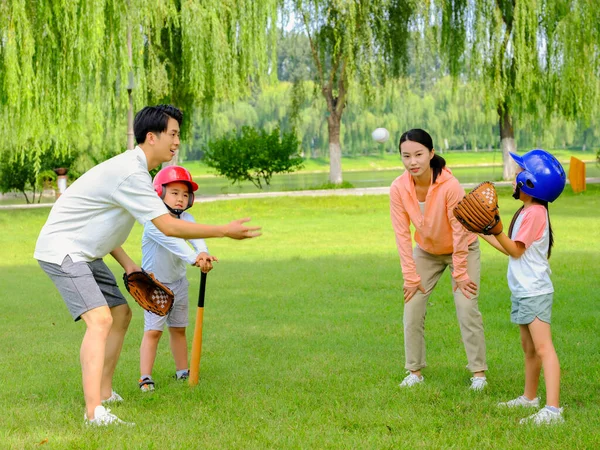 Bonne famille de quatre personnes jouant au baseball dans le parc — Photo