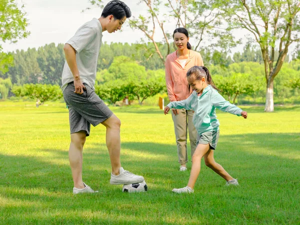 Heureuse famille de trois personnes jouant au football dans le parc — Photo