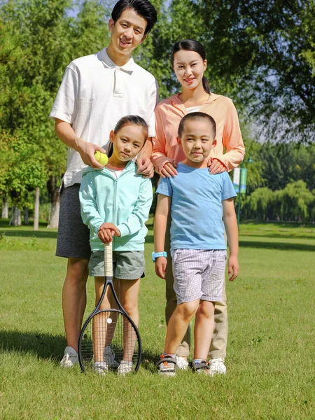 Família feliz de quatro jogando tênis no parque — Fotografia de Stock