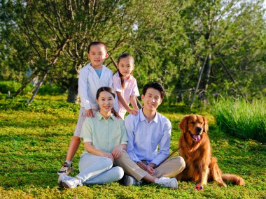 Dört kişilik mutlu bir aile ve parkta evcil bir köpek.