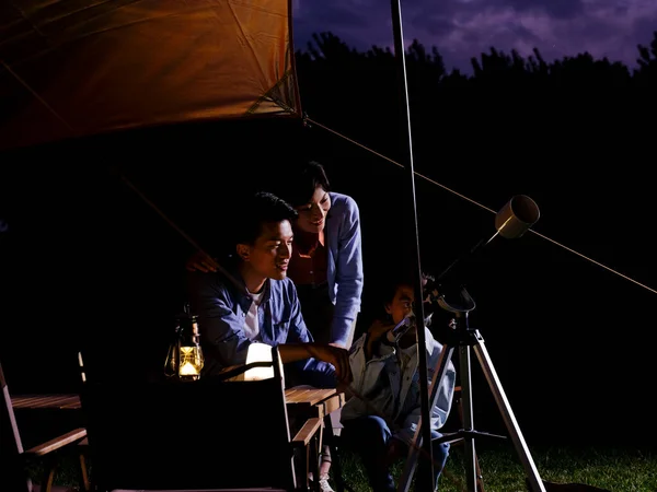 Una famiglia felice di tre persone che utilizzano telescopi all'aperto — Foto Stock