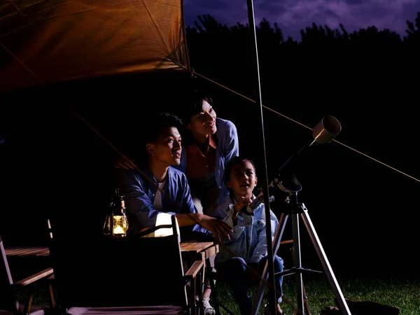 Egy boldog háromtagú család teleszkópokkal a szabadban. — Stock Fotó
