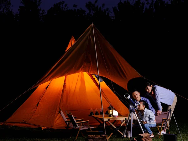 A happy family of three using telescopes outdoors — Stock Photo, Image