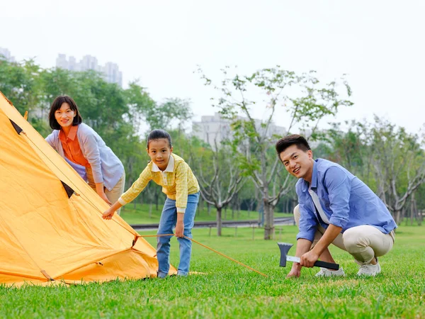 Eine glückliche dreiköpfige Familie baut draußen ihre Zelte auf — Stockfoto