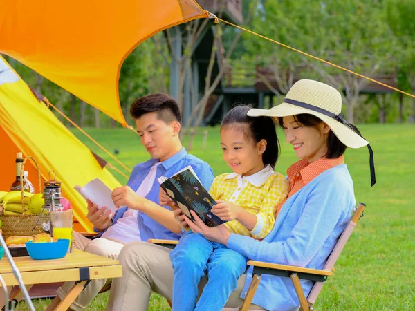 Szczęśliwa rodzina z trójką dzieci czytająca na zewnątrz — Zdjęcie stockowe