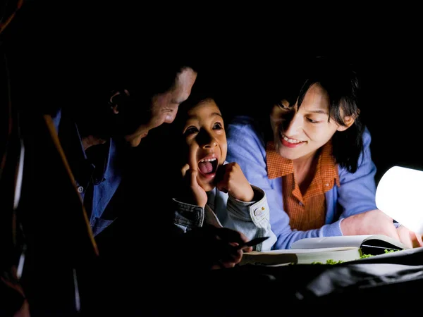 Eine glückliche dreiköpfige Familie liest und macht sich nachts Notizen — Stockfoto