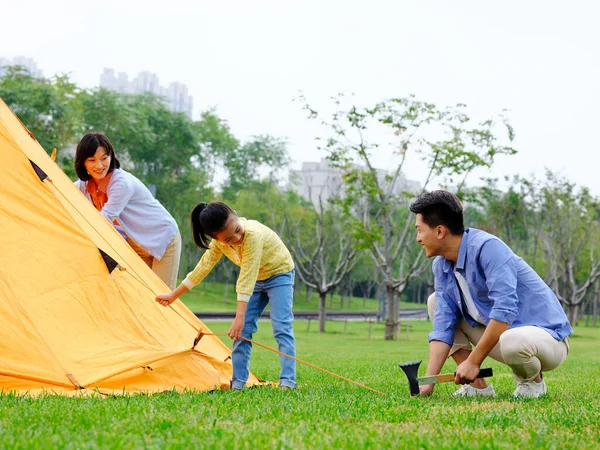 En lycklig familj med tre uppsatta tält utomhus — Stockfoto